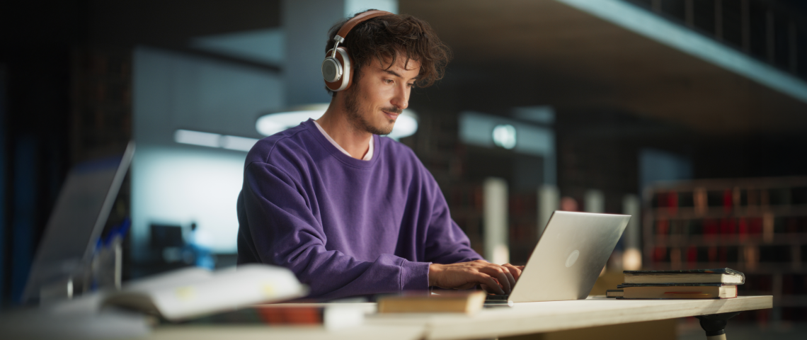 Man wearing headphones looks at his computer in office.