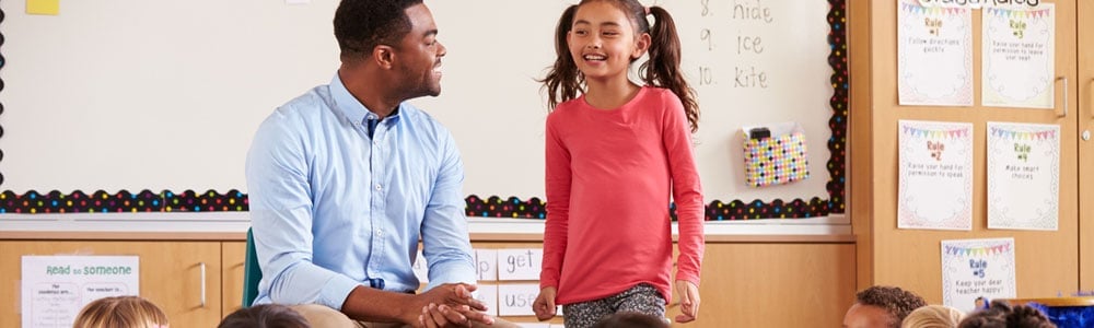 Special education teacher laughing with student in classroom setting