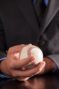 Person in business suit holding baseball in hand