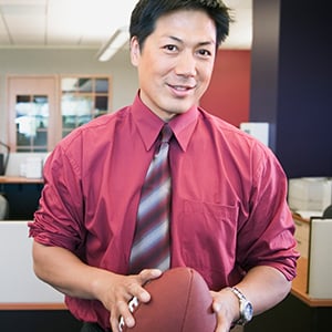 Sports manager holding a football in an office setting