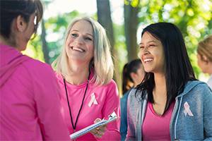 Two nonprofit workers at a breast cancer awareness event talking with a participant