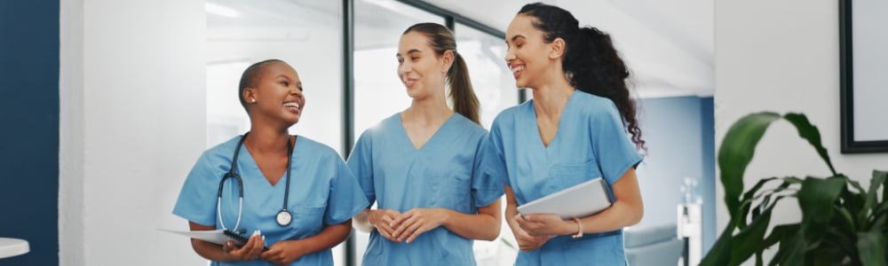 Three nurses laughing in hospital hallway